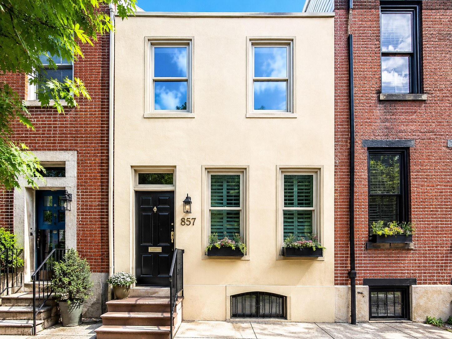Cream stucco Philadelphia rowhome exterior in Fairmount with black front door and brick neighboring homes